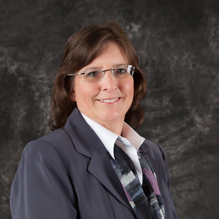 Corporate headshot of a woman with glasses on a dark background
