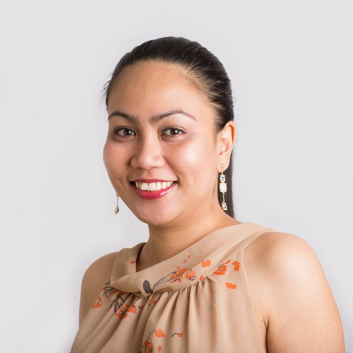 On-location headshot of a smiling woman in a black top on a white background