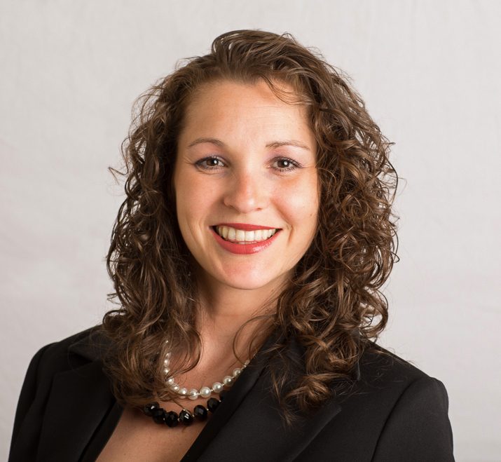 On-location headshot of a woman with curly hair against a dark background